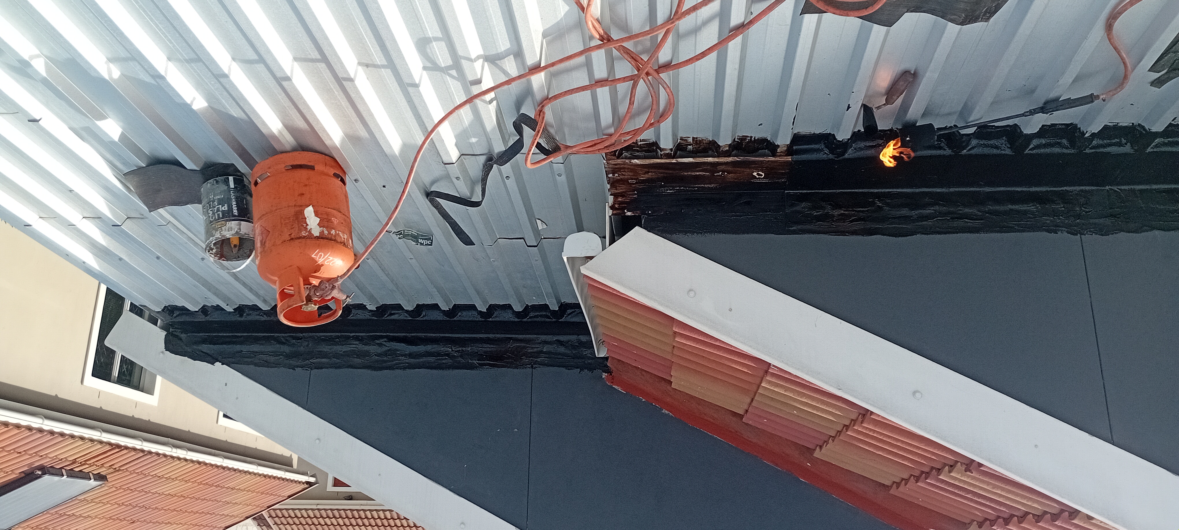 Torch-on waterproofing installation in progress on a metal roof