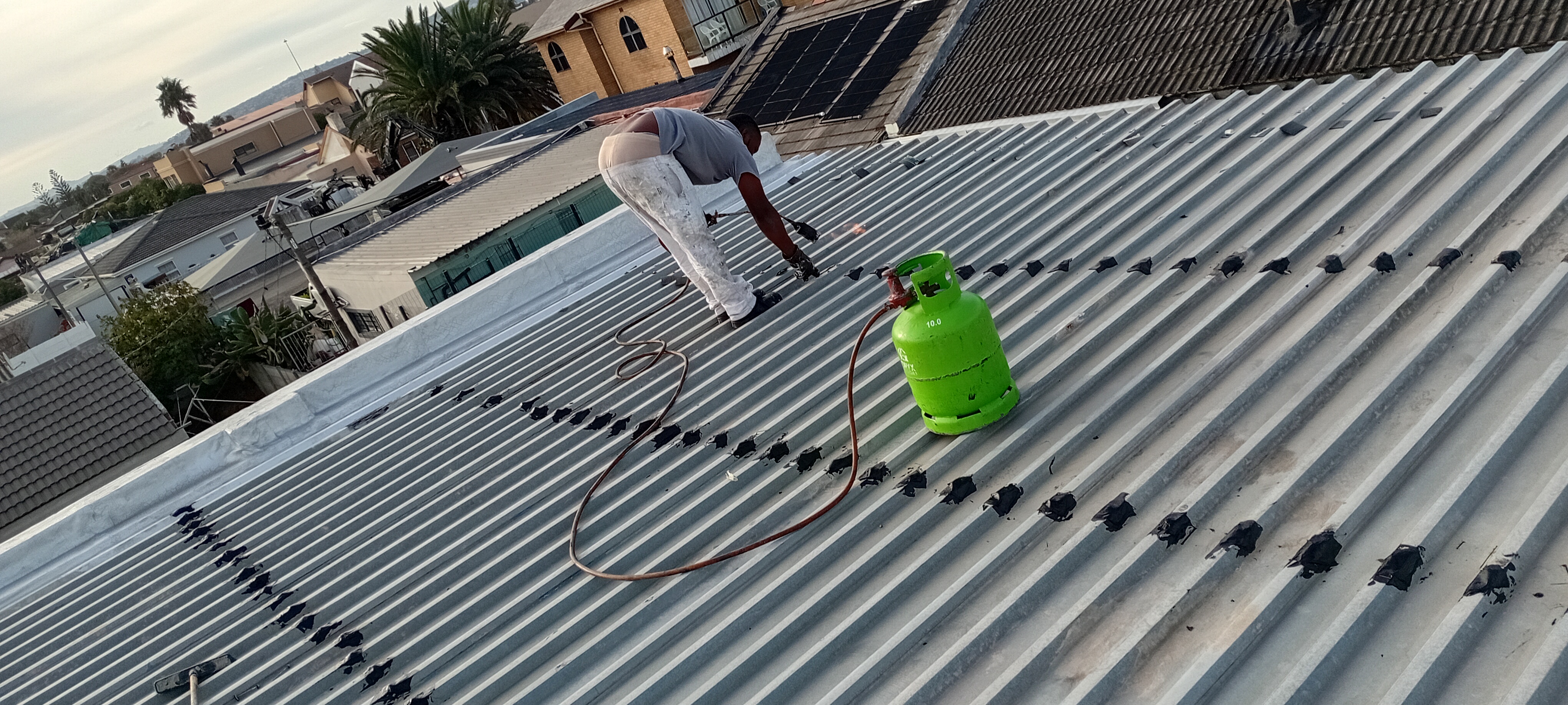 Technician working across a corrugated roof repair job